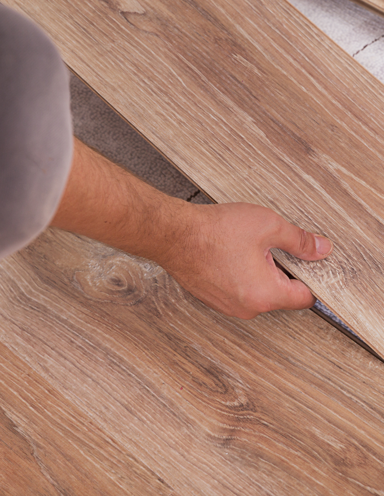 Hands installing vinyl plank. 